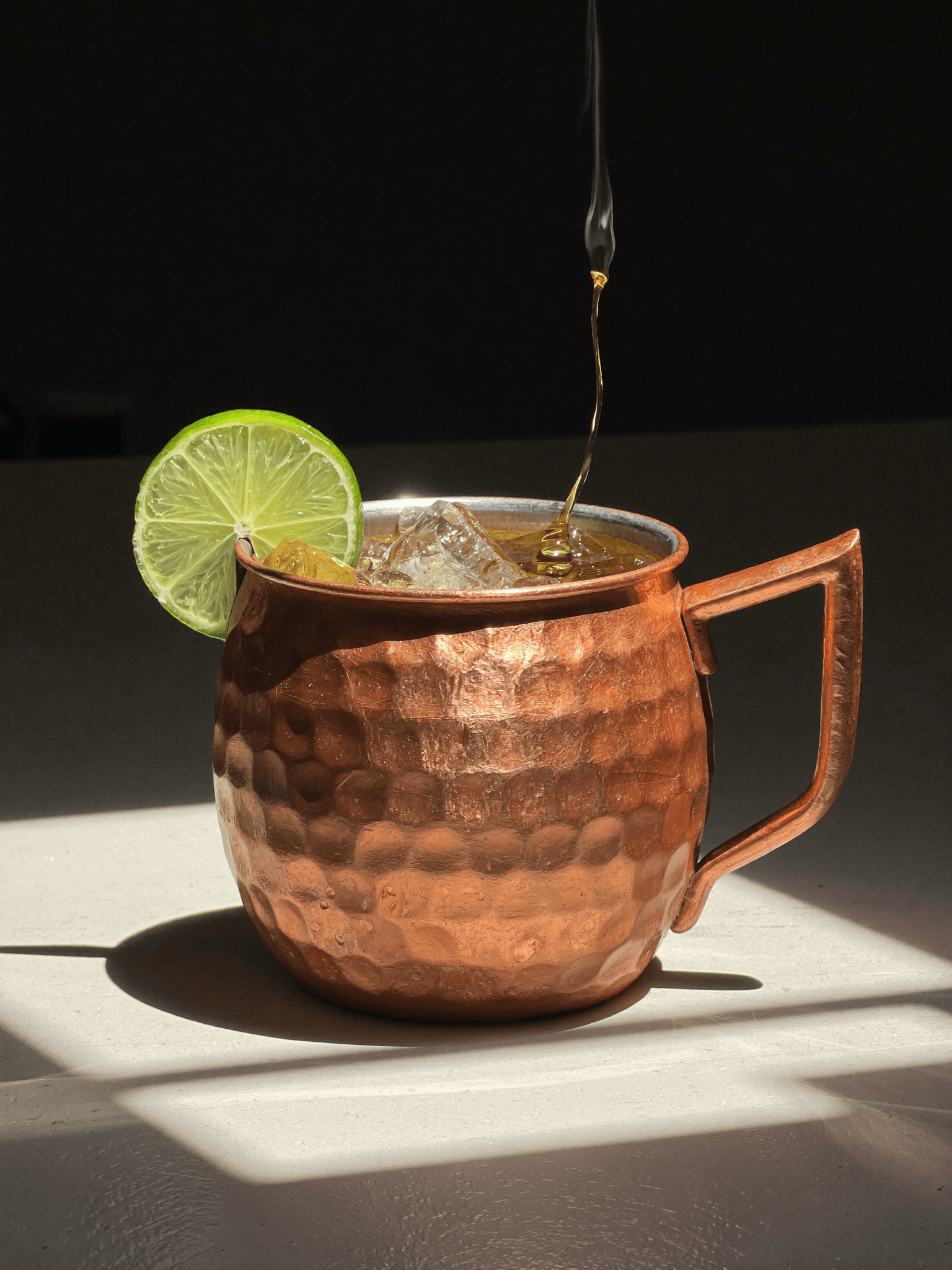 A Pombay Cane Vodka Moscow Mule in a copper mug with lime