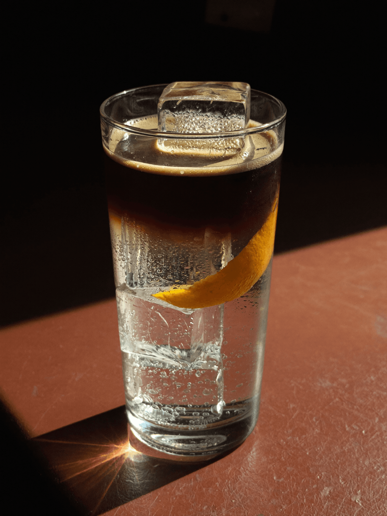 A Pombay coffee tonic highball with an orange peel