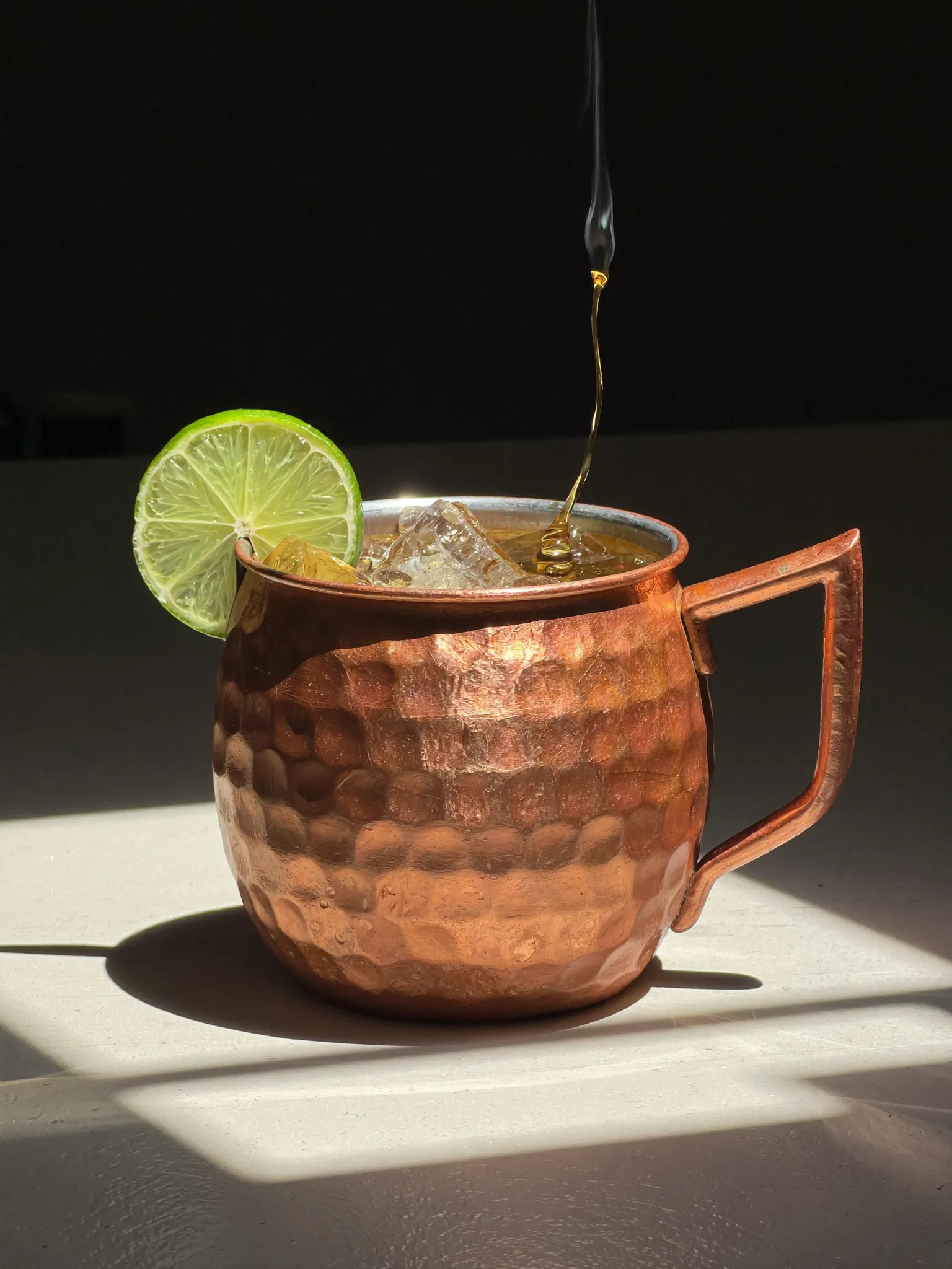 A Pombay Cane Vodka Moscow Mule in a copper mug with lime